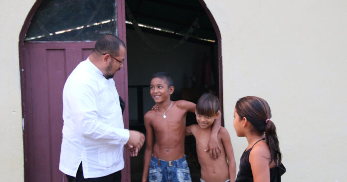 Padre Angel mit Kindern vor der Kapelle in Guarataro, Venezuela