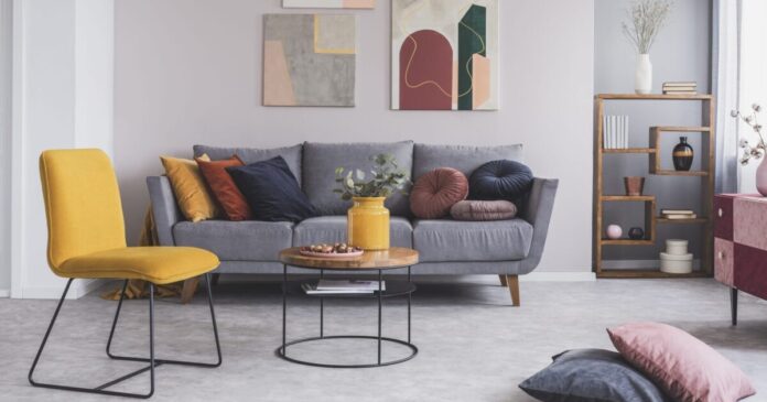 ein angenehmes, sauberes Wohnzimmer mit grauem Sofa und gelben Akzenten