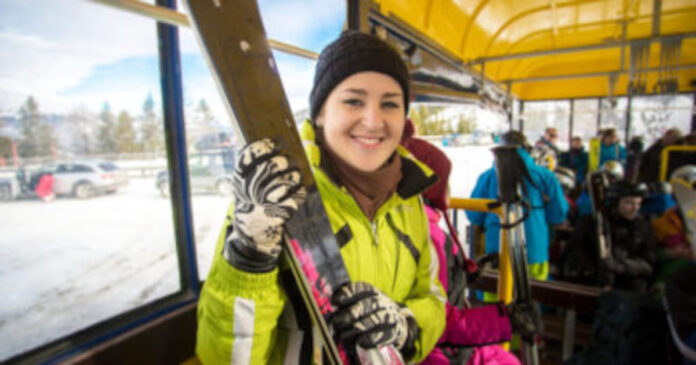 Eine Skifahrerin faehrt Bus mit ihren Ski 1