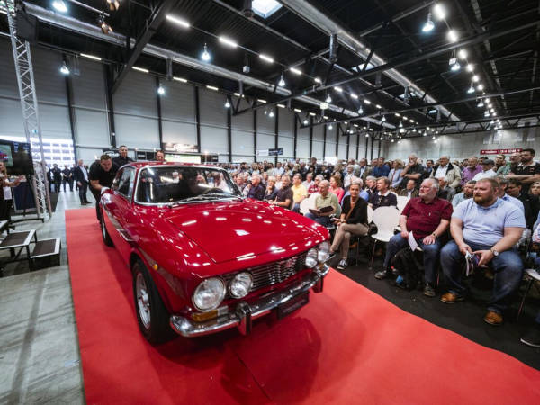 Ein rotes Auto glänzt auf dem roten Teppich vor den Publikumsreihen.