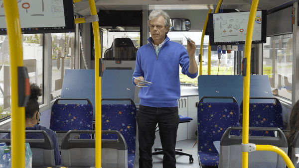 Projektleiter Rainer Walser steht im Bus, erklärtdas Bild auf dem Bildschirm hinter ihm.