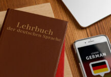Sprachschulen haben eine besondere Herausforderung Ein Deutsch-Lehrbuch plus ein Handy mit Deutsch-App liegen auf dem Tisch