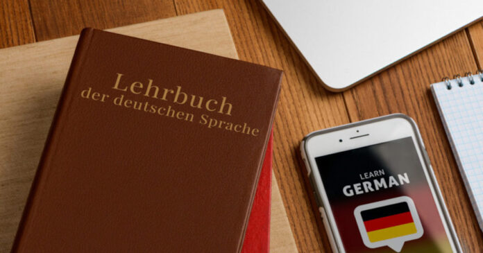 Ein Deutsch-Lehrbuch plus ein Handy mit Deutsch-App liegen auf dem Tisch