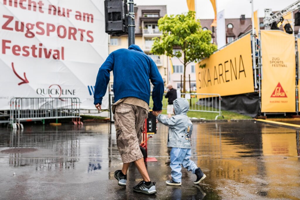 Vater mit Kind laufen durch verregnetes Zug Sports Festival