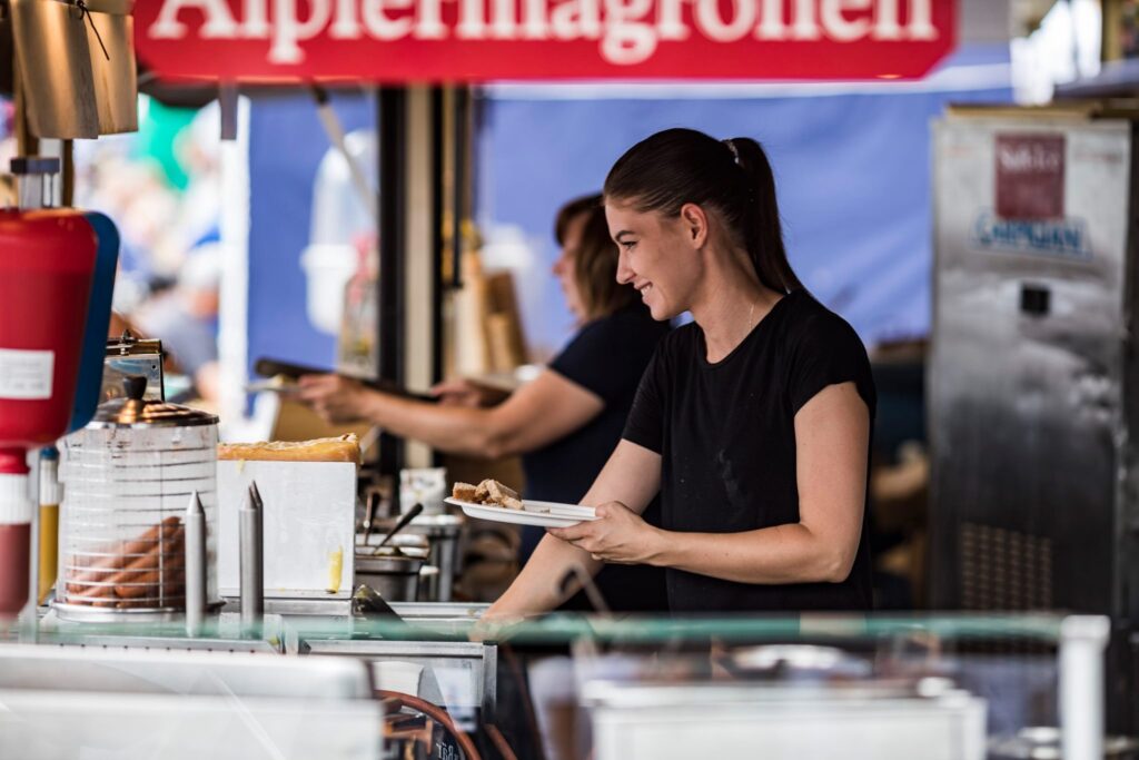 Frau gibt Essen aus an Essensstand am Zug Sports Festival