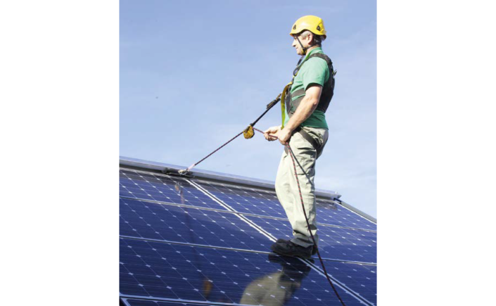 Mann ist gesichert auf Dach mit Photovoltaikanlage