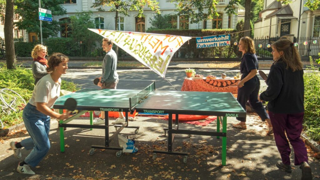Teenager spielen Ping-Pong auf einem Parkplatz.