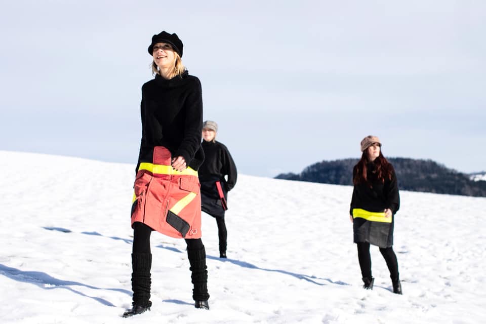 Drei Models präsentieren die Röcke aus Feuerwehruniformen in einer Schneelandschaft.