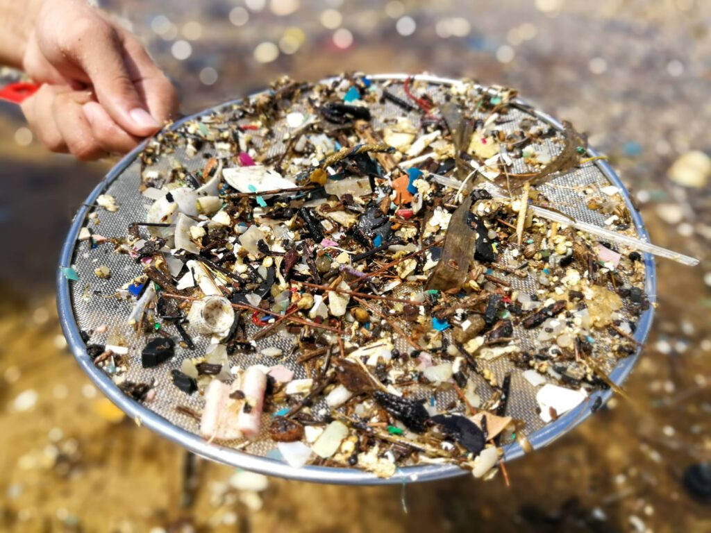 Mit einem Sieb lassen sich grosse Plastikstücke vom Sand entfernen.