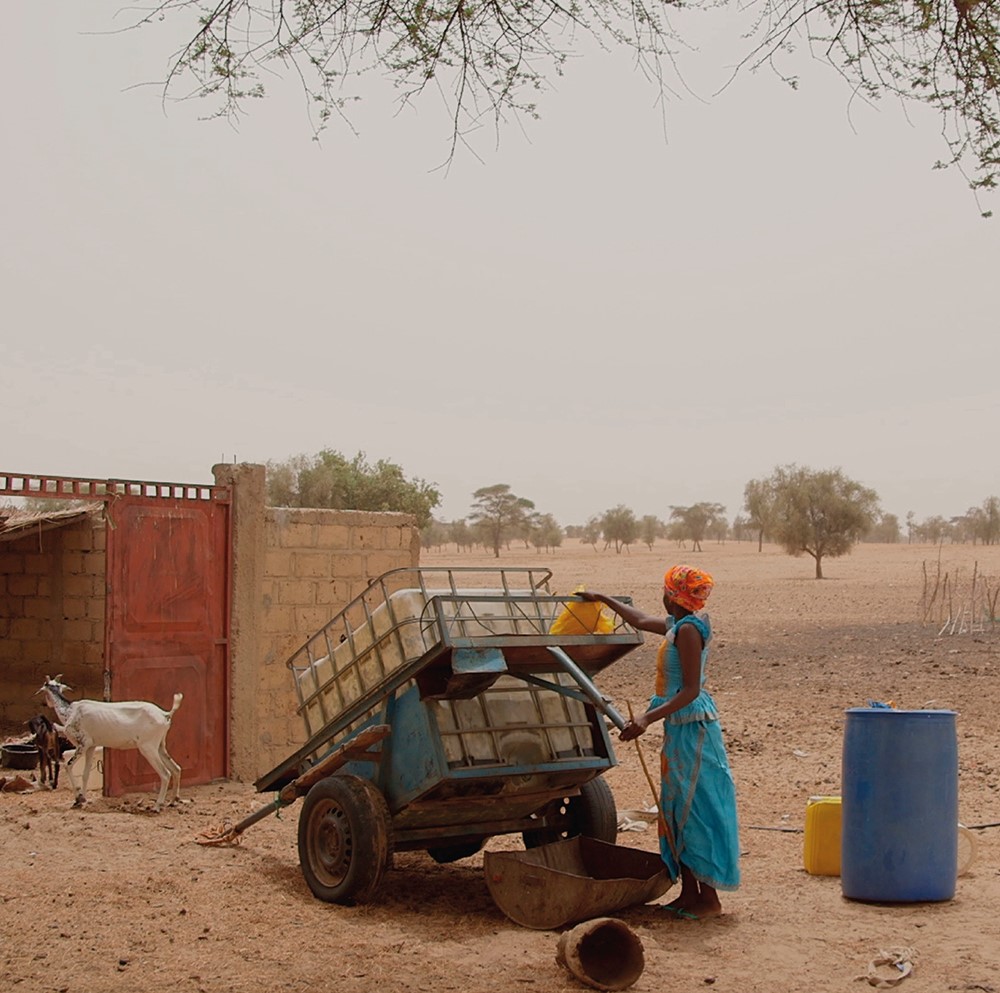 In Senegal lädt ein Mädchen einen Wasserkanister auf einen Wagen.