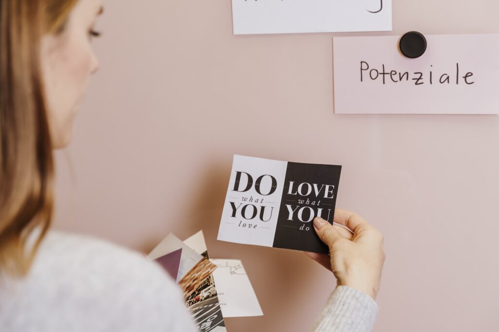 Frau schaut auf ein Kärtchen, auf welchem steht "do what you love, love what you do". Keine Chance auf Selbstsabotage!