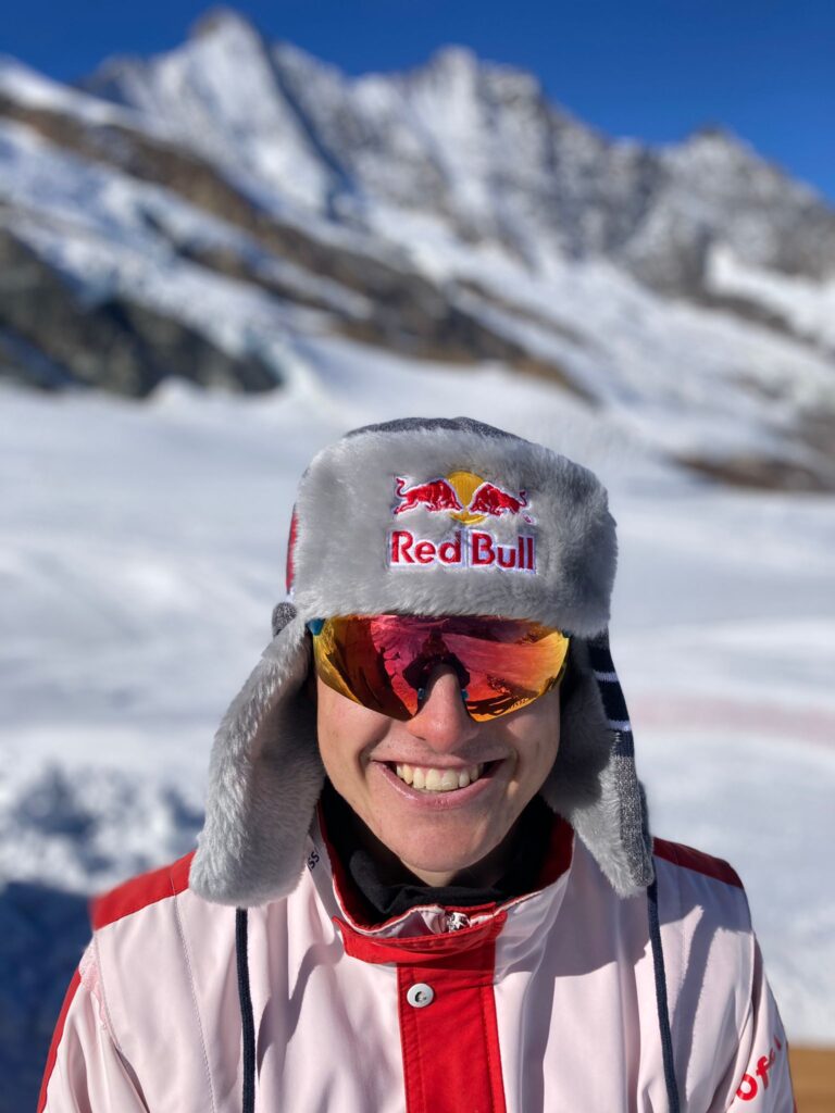Noé Roth grinst in die Kamera. Er trägt eine Winterkappe mit dem Logo von Red Bull.