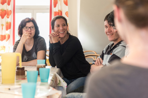 Vier Menschen sitzen um einen Tisch und lächeln