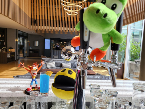 Ein Bild vom Gaming-Hotel, auf dem Stofftiere von Pac-Man, Yoshi, eine Figur von Crash Bandicoot und ein Sonic Mojito zu sehen sind.