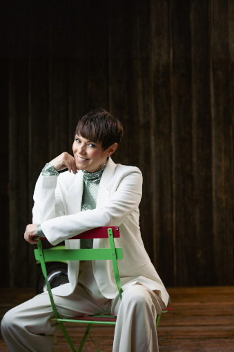 Francine Jordi im weissen Anzug auf einem grünen Stuhl