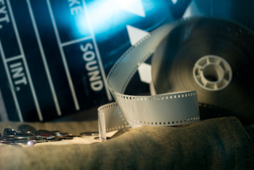 Münzen auf Tisch neben Filmrolle und Filmklappe