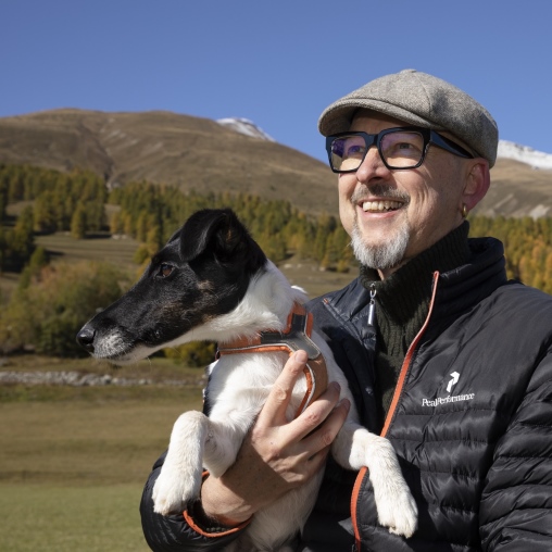 Marc Bodmer steht mit seinem Hund im Arm in der Natur