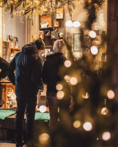 Zweil Leute blicken zusammen durch das Schaufenster eines Ladens an den Bruchweihnachten.