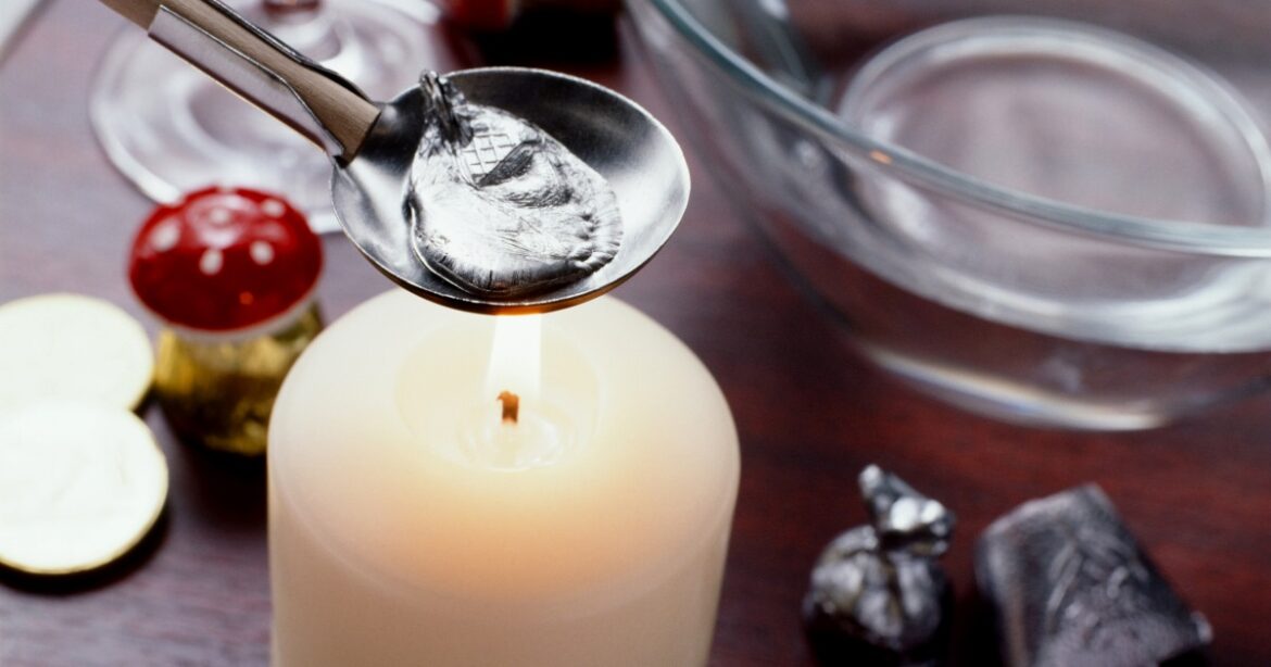 Über einer Kerze wird mit einem Löffel das Bleigiessen durchgeführt.