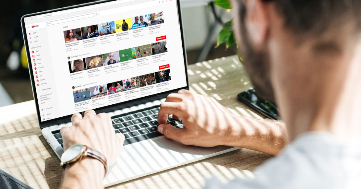 Weisser junger Mann surf mit Macbook auf Youtube