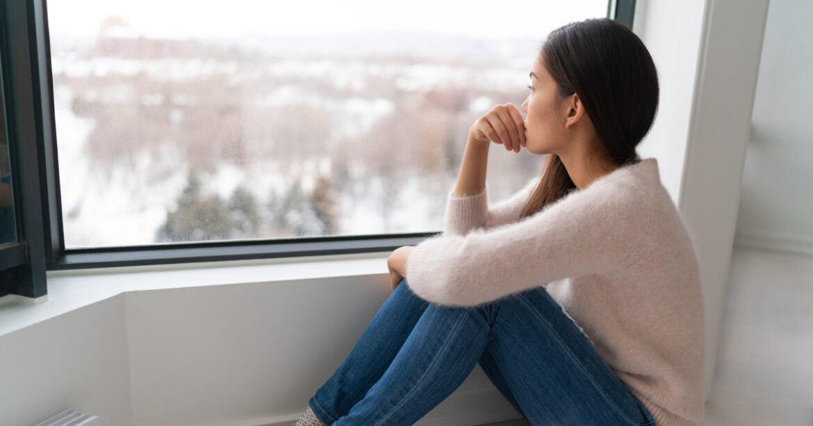 Junge asiatische Frau sitzt am Fenster