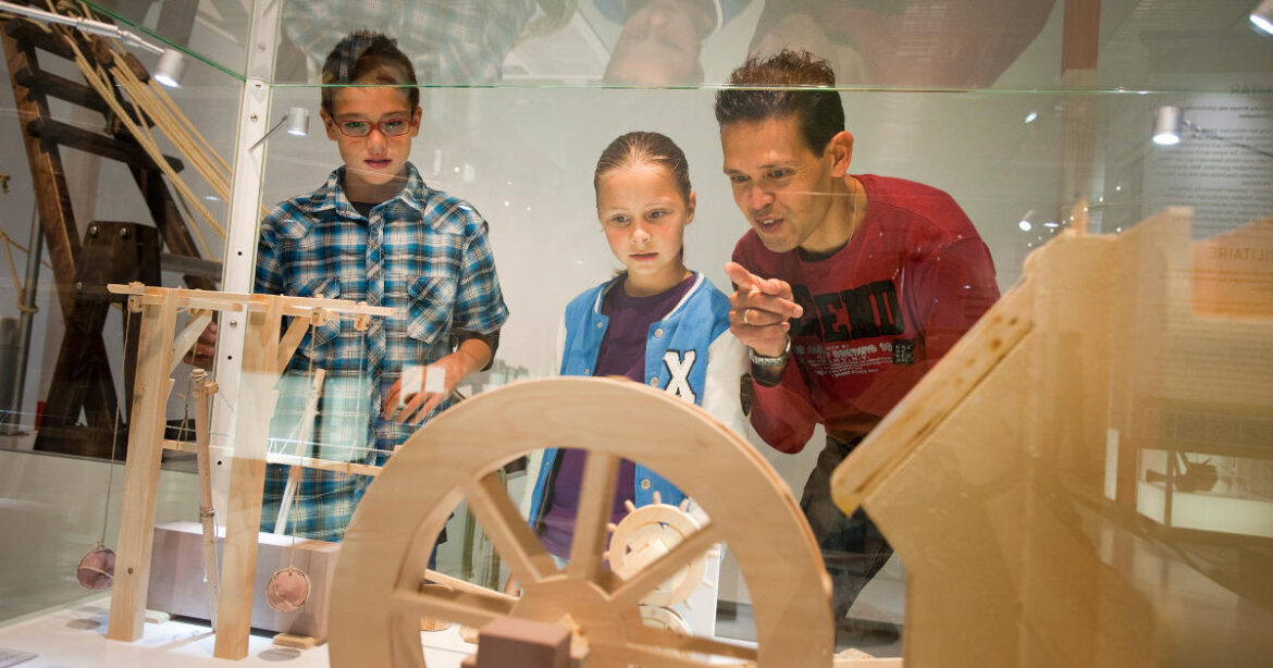 Mann erklärt zwei Kindern die Holzmodelle