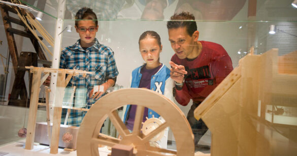 Mann erklärt zwei Kindern die Holzmodelle