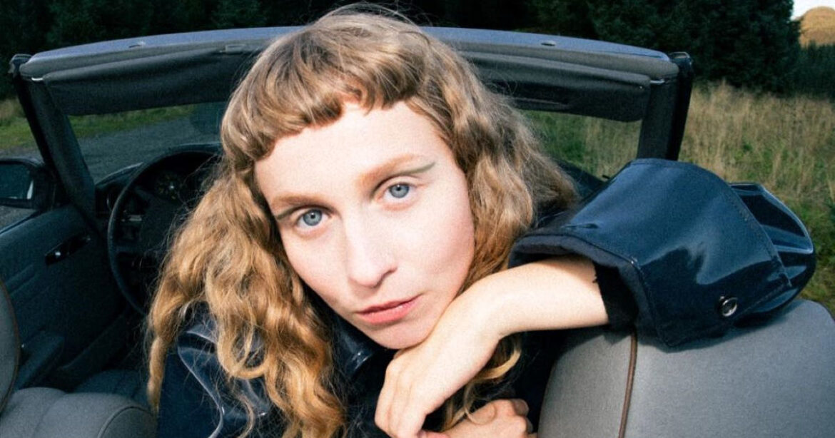 Die norwegische Musikerin Moyka posiert in einem Cabriolet in der Natur