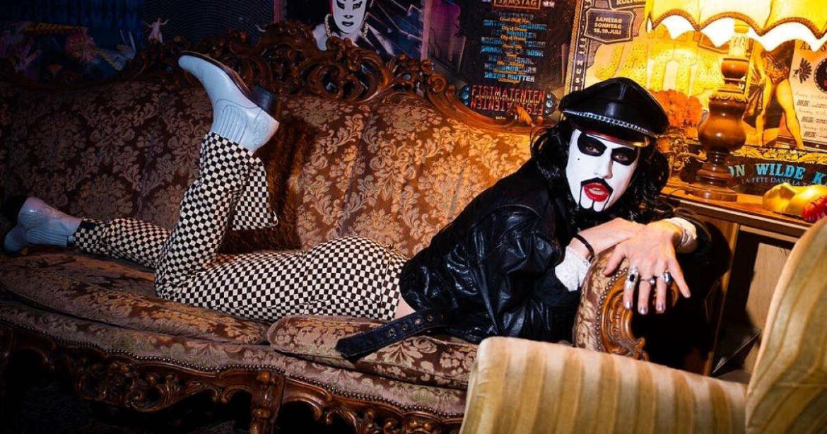 Person mit Lederjacke und KISS-Make-up auf Sofa