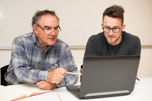 Älterer Chef und jüngerer Mitarbeiter vor Laptop