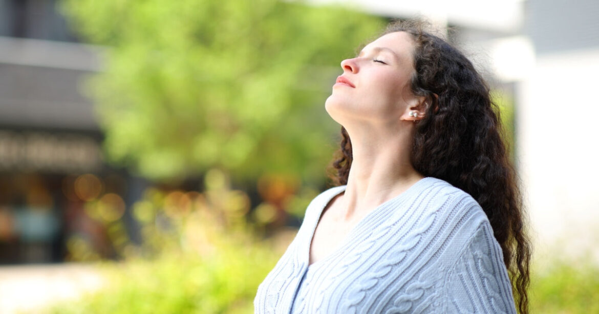 Eine Frau atmet draussen tief ein