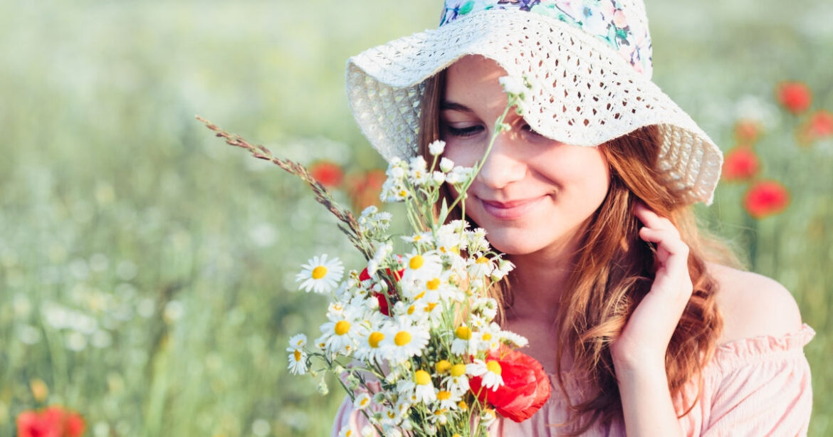 Frau steht mit Blumen in der Hand in einem Blumenfeld