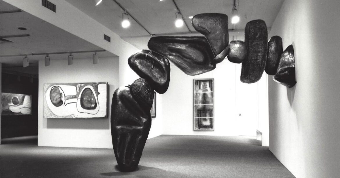 Eine Skulptur aus Metallmuscheln verbindet eine Wand mit dem Boden.