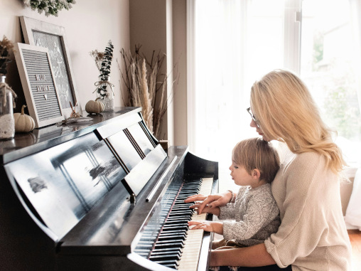 Junge Frau mit Kleinkind am Klavier