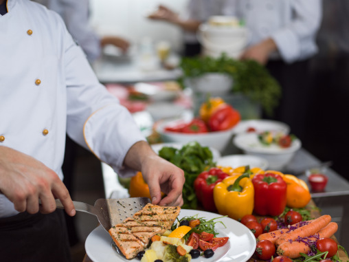 Koch richtet Essen auf Teller an