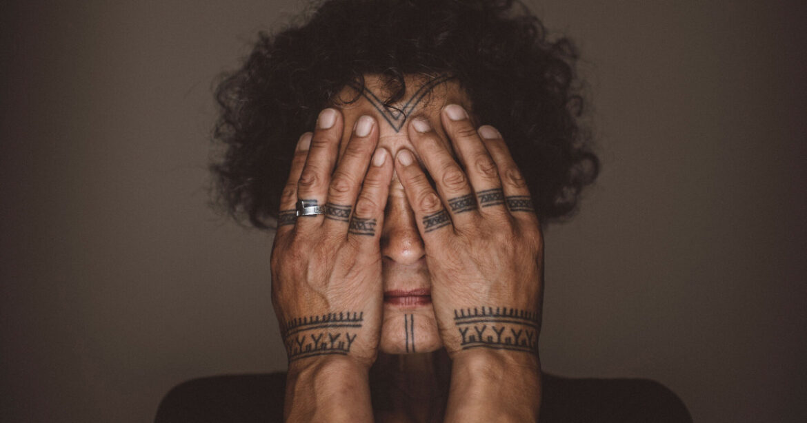 Indigene ältere Frau hält sich die Hände vor das Gesicht