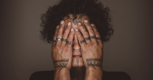 Indigene ältere Frau hält sich die Hände vor das Gesicht