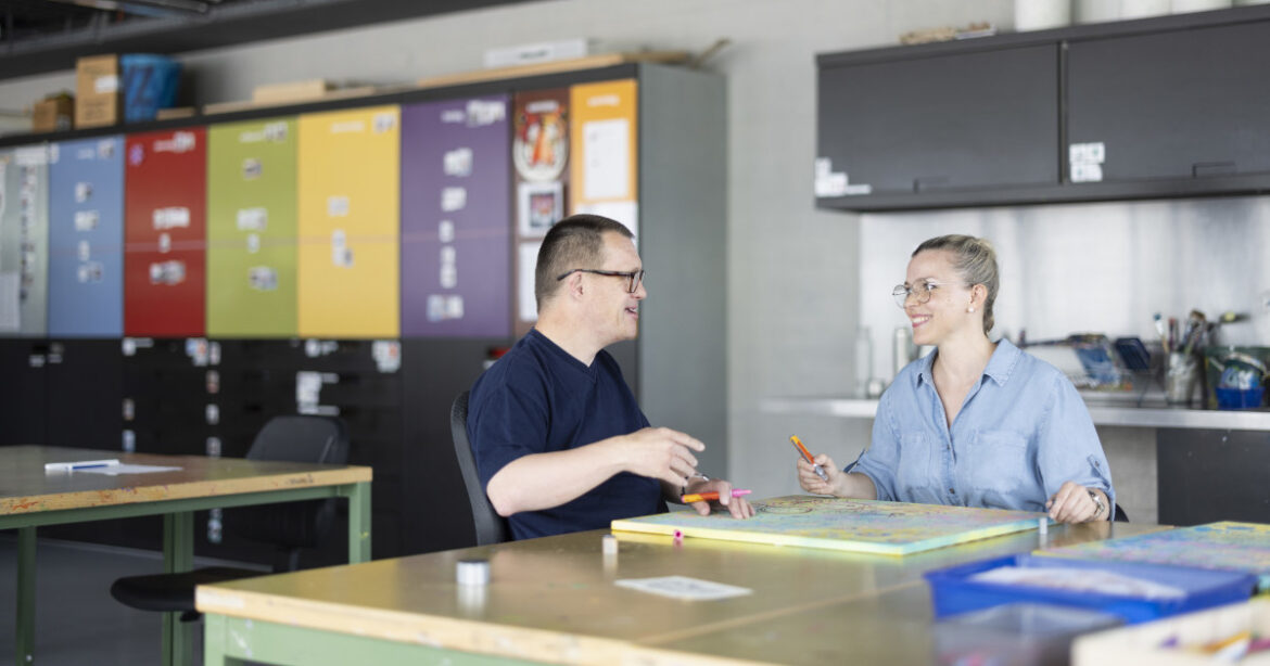 Junge Frau sitzt mit Mann an einem grossen Tisch