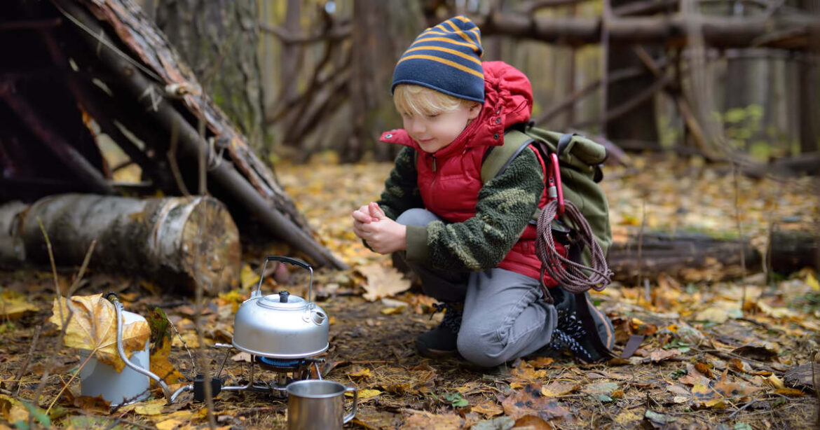 Kleiner Junge in Wald mit Pfadfinderausrüstung
