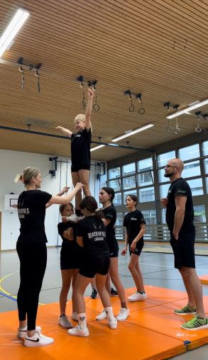 Kinder und Trainer beim Cheerleading Training in der Turnhalle