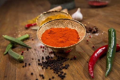 Gewürze in Schalen plus Chilischoten, die auf dem Tisch liegen
