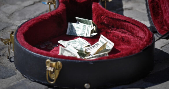 ein offener Gitarrenkoffer mit Geldnoten drinliegend