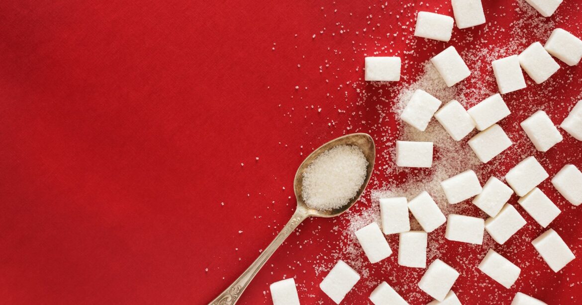zucker, sugar cubes and a spoon on a red surface
