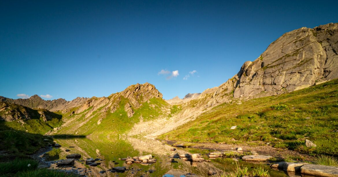 Wanderrouten in Uri. green grass field and brown mountain under blue sky during daytime