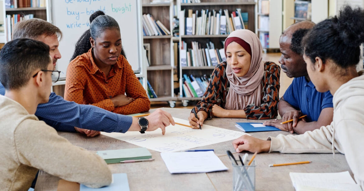 Studierende sitzen an einem Tisch und diskutieren