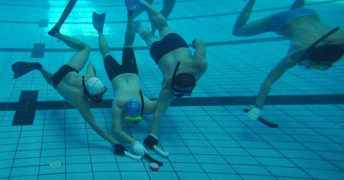 Spieler ringen unter Wasser um den Puck.