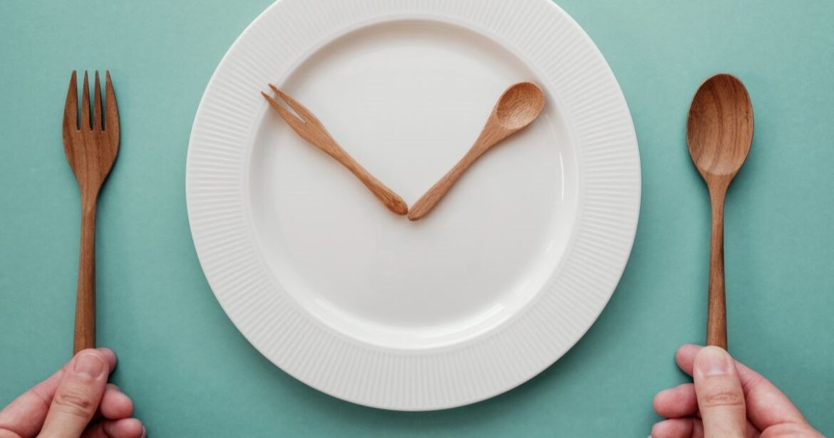 Ein leerer Teller mit Besteck, das wie Uhrzeiger auf einer Uhr auf dem Teller platziert sind.