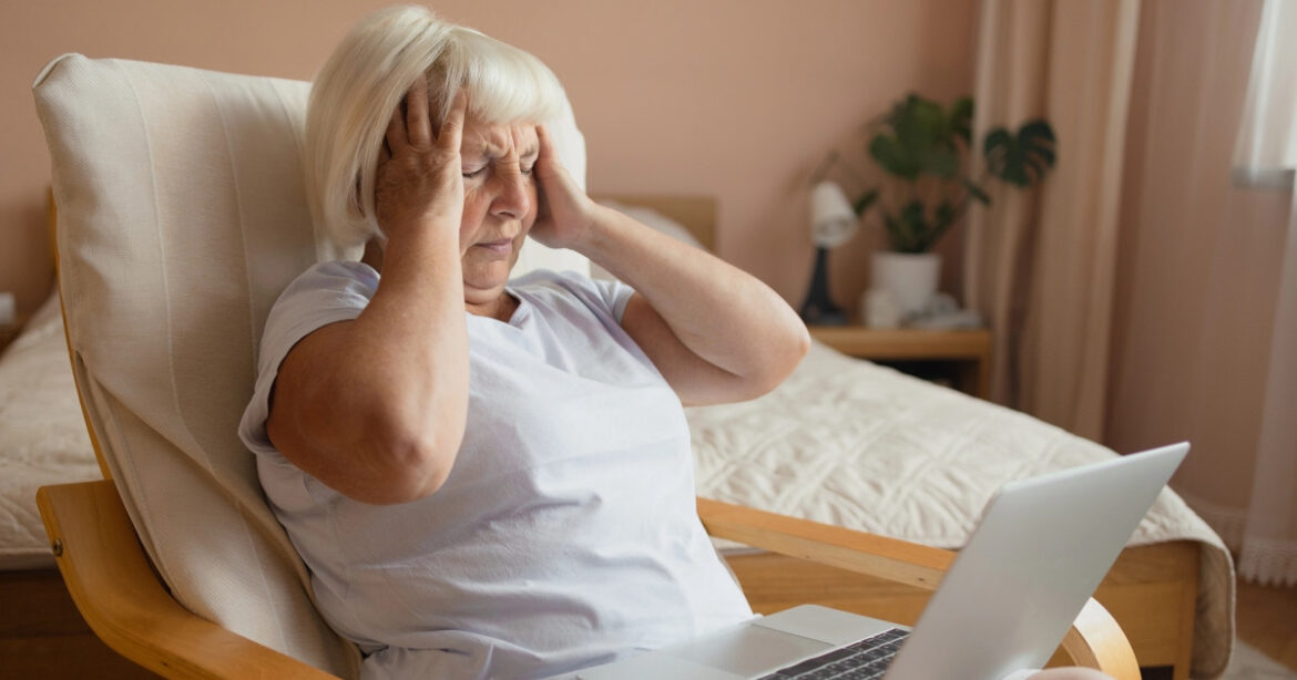 Eine ältere Frau sitzt am Laptop und verzweifelt