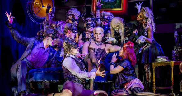 Die DarstellerInnen von der Rocky Horror Show sitzen aneinander angelehnt auf der Bühne, posieren.