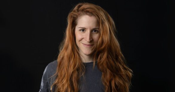 Judith Erdin alias Streusel lächelt vor einem schwarzen Hintergrund in die Kamera.